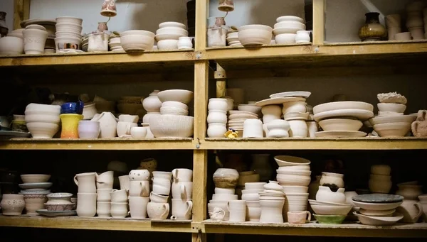Muchos diferentes cerámica de pie en los estantes en un taller — Foto de Stock