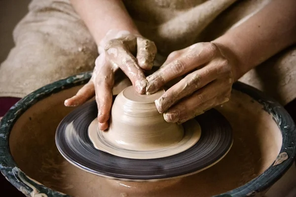 Potter hands creating a product from clay on potters wheel