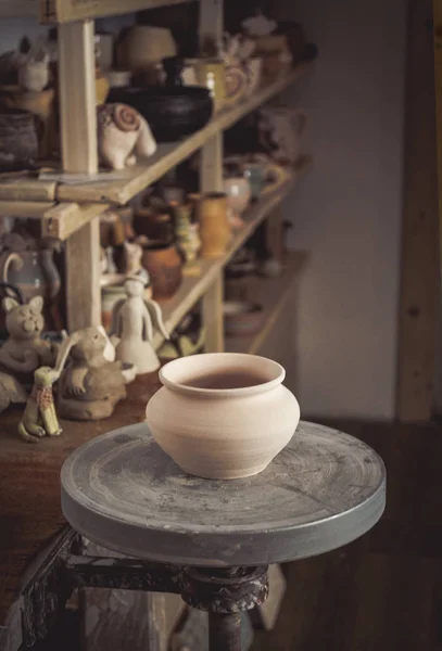 Panela de barro em primeiro plano e prateleiras com cerâmica - no segundo — Fotografia de Stock