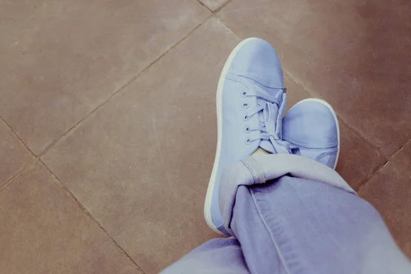 Feet jeans sneakers floor Stock Image