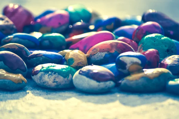 Muchos guijarros pequeños cubiertos con pintura multicolor yacen en la superficie — Foto de Stock