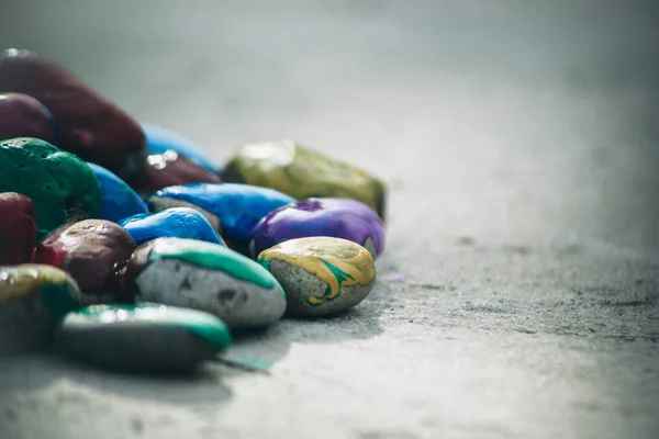 Många små stenar täckta med mångfärgad färg ligger på ytan — Stockfoto