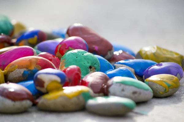 Molti piccoli ciottoli ricoperti di vernice multicolore si trovano sulla superficie — Foto Stock