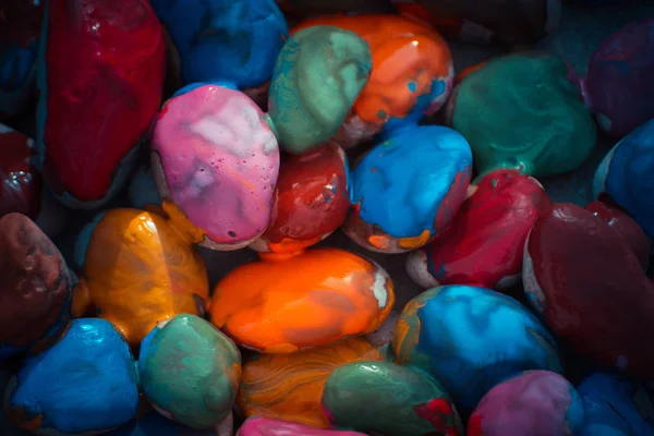 Many small pebbles covered with multicolored paint lie on surface — Stock Photo, Image