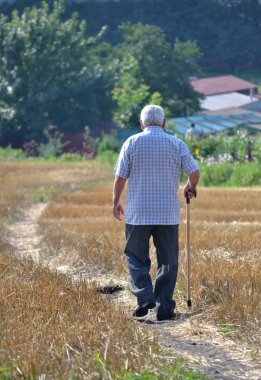 gri saçlı adam yol boyunca yürürken