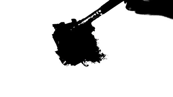 Smetar svart färg med en borste på vitt papper. — Stockvideo