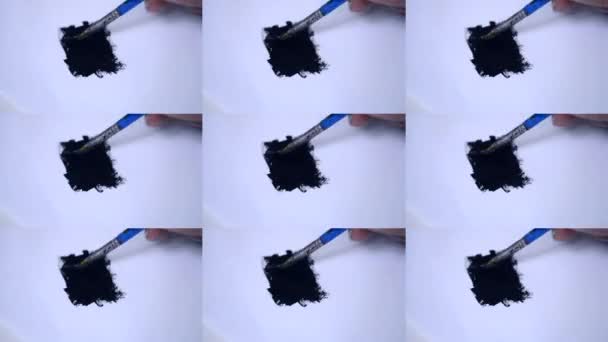 Размазывание черной краской кистью на белой бумаге . — стоковое видео