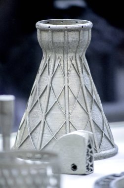 Metal 3D yazıcıya yazdırılmış nesneyi tutan adam.