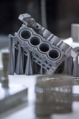 Metal 3D yazıcıya yazdırılmış nesneyi tutan adam.