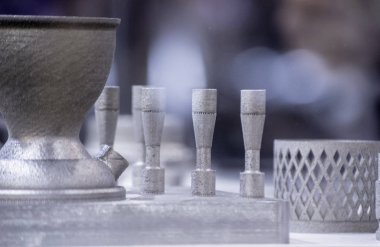 Metal 3D yazıcıya yazdırılmış nesneyi tutan adam.