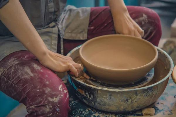 Potter holds round clay plate in his hands.