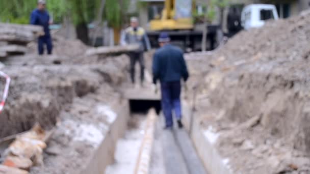 Trabajadores con grúa de construcción cubren nuevas tuberías de agua con losas de hormigón — Vídeos de Stock