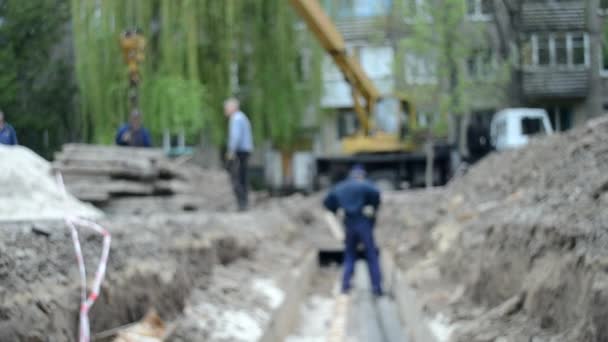 Trabajadores con grúa de construcción cubren nuevas tuberías de agua con losas de hormigón — Vídeos de Stock