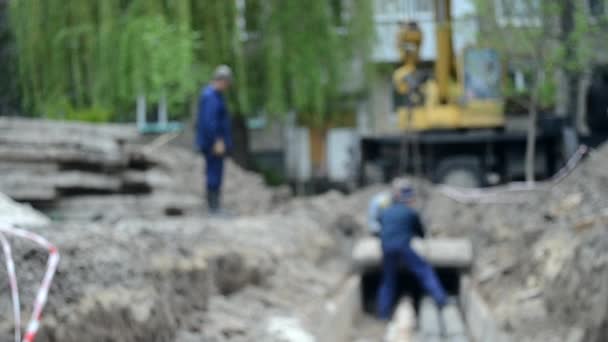 Рабочие со строительным краном покрывают новые водопроводные трубы бетонными слябами — стоковое видео