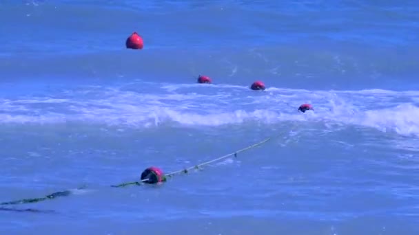 Rote umschließende Bojen schwimmen im Sommer auf Wellen im Meer — Stockvideo