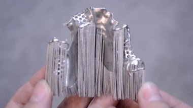 Metal 3D yazıcıya yazdırılmış nesneyi tutan adam.