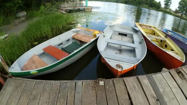 Old iron frayed and shabby boat noses tied to wooden dock — Stock Video