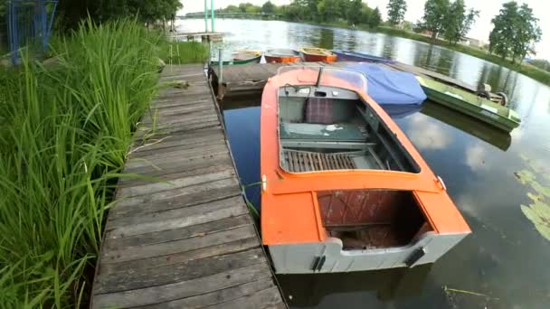 Old iron frayed and shabby boat noses tied to wooden dock — Stock Video