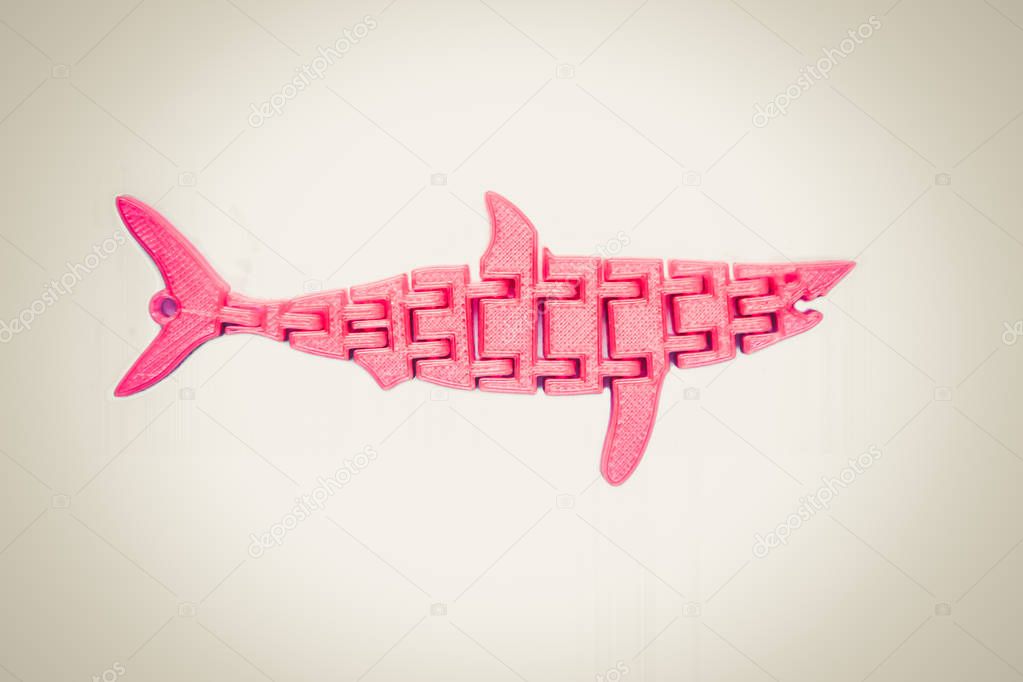 Bright light pink object in shape of fish toy printed on 3d printer