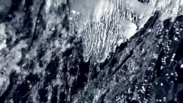 Het ontdooien van ijs aan de rand van een waterval beek close-up. Met geluid. — Stockvideo