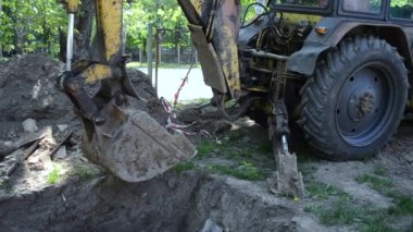 Traktör yer çukurunun yanında duruyor. Kazıcı yere yakın çekim deyıyıp yığıyor.