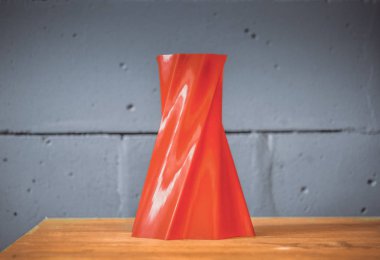 Mavi tuğla duvar arka plan üzerinde 3d yazıcı tarafından yazdırılan parlak kırmızı nesne vazo.