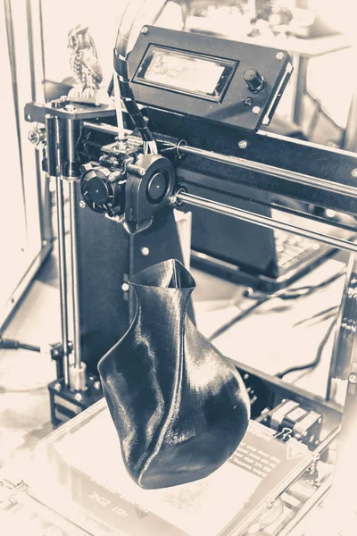 Old vintage style. 3D printer printing a model in the form of black vase.