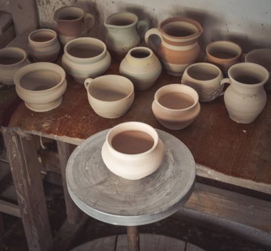 Masada çömlek içinde bir sürü kil saksı var.