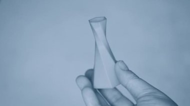 Kişi ellerini tutar ve 3D yazıcıda yaratılan kırmızı nesneyi görür.