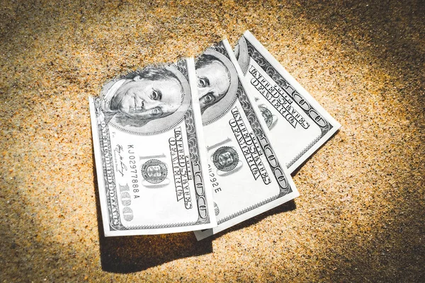 Money dolars half covered with sand lie on beach close-up. Dollar bills partially buried in sand. Three hundred dollars buried in sand on sea ocean beach Concept finance money holiday relax vacation