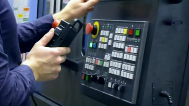Kontrol panelinde çalışan adam endüstriyel bir makineyle çalışıyor.