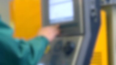 Üretim makinesinin kontrol panelinin arkasında çalışan kişi