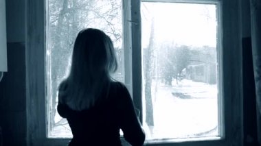 Kadın kışın evinde bir pencere açıyor..