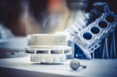 Metal 3D yazıcıya yazdırılmış nesneyi tutan adam.