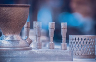 Metal 3D yazıcıya yazdırılmış nesneyi tutan adam.