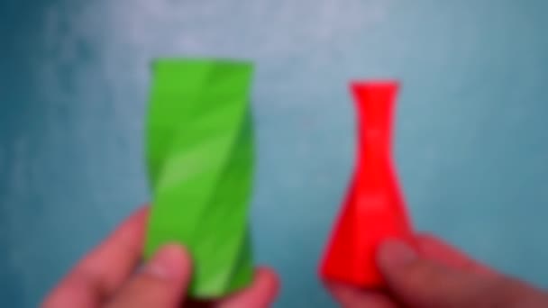 Wazige achtergrond. De persoon houdt zijn handen vast, kijkt naar rood groene objecten — Stockvideo