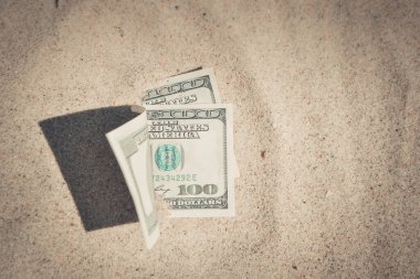 Kumsalda kumla kaplanmış paranın yarısı yakın planda duruyor.