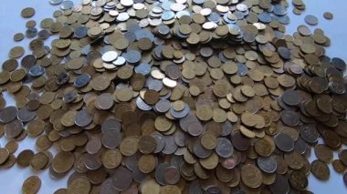 Eline bir avuç bozuk para alır ve masanın üstüne atar..