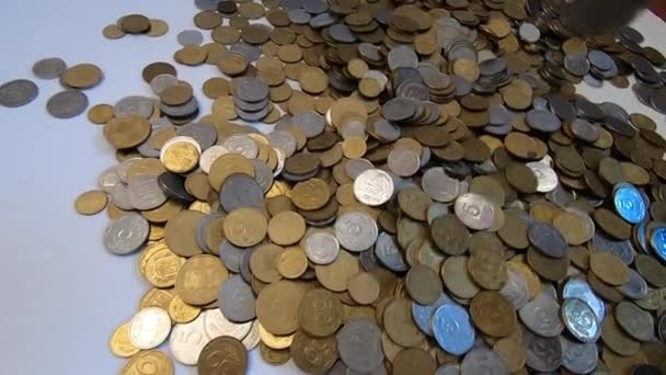 Person nimmt eine Handvoll Münzen in die Hand und wirft sie über Münzen auf den Tisch. — Stockvideo