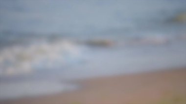Arka plan bulanık. Karadeniz 'in kumlu sahilinde küçük dalgalar var.