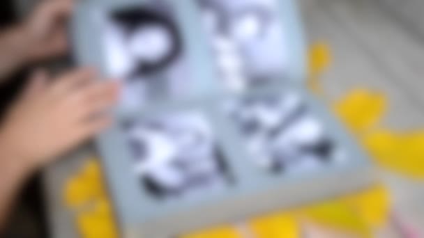Latar belakang kabur. Girl leafing through a photo album with old photos — Stok Video