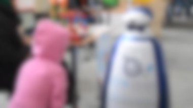 Arka plan bulanık. Robot serginin ziyaretçileriyle iletişim kuruyor.