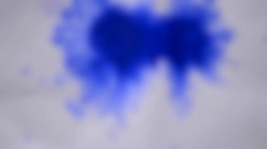 Arka plan bulanık. Renkli boya beyaz ıslak kağıda sıçrar. Yaratıcı soyut