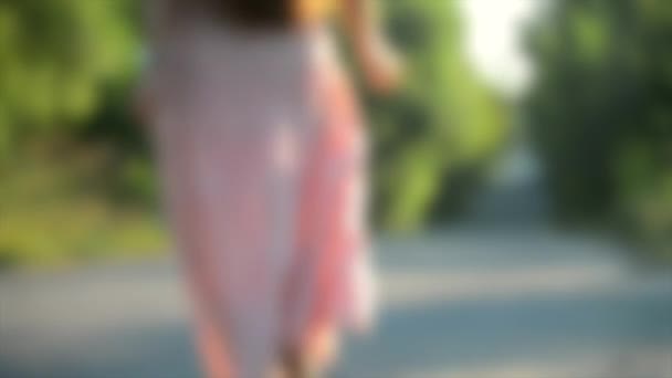 Sfondo sfocato. Bruna ragazza in un abito rosa che cammina su strada da asfalto — Video Stock