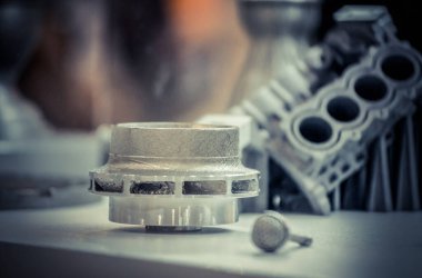 Metal 3D yazıcıya yazdırılmış nesneyi tutan adam.