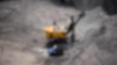 Arka plan bulanık. Büyük endüstriyel kazıcı granit ocağında çalışıyor.