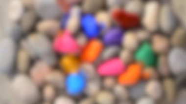 Arka plan bulanık. Gri pürüzsüz taşları farklı renklerde boyayan HD 1080