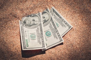 Kumsalda kumla kaplanmış paranın yarısı yakın planda duruyor..