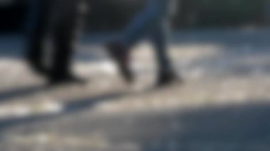 Arka plan bulanık. İnsanlar gün batımında meydanda yürürler..