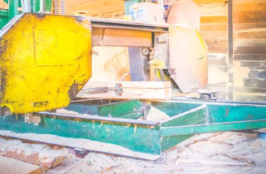 Bıçkıhane. Teçhizat testere makinesindeki makine kayıtları tahta tahtalardaki ağaç gövdesini testereyle kesiyor. Ahşap talaşı ahşap ahşap işçiliğini kesiyor.